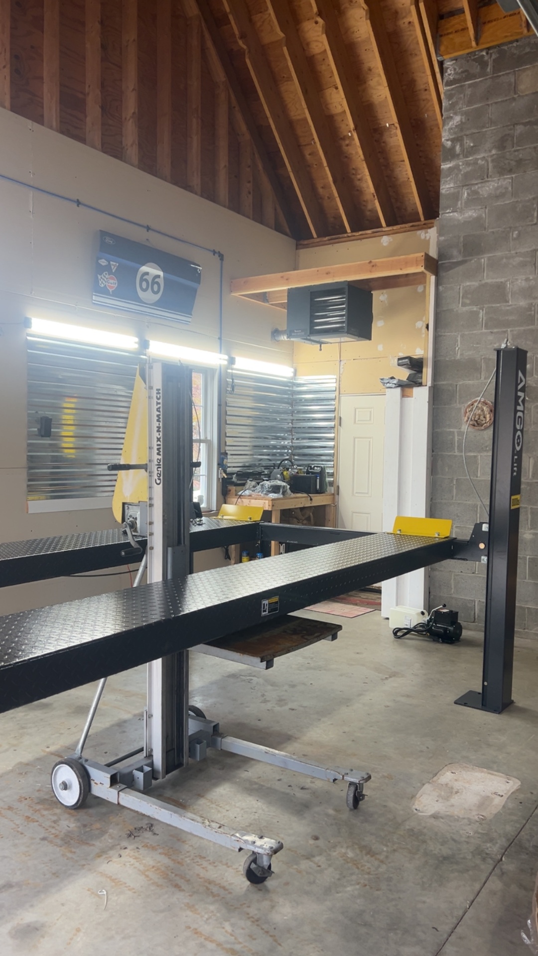 Four-post AMGO lift installed under a vaulted wood-beam garage