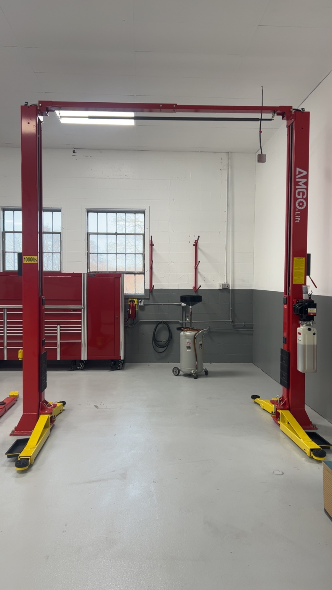 Red AMGO two-post lift installed in a clean commercial shop