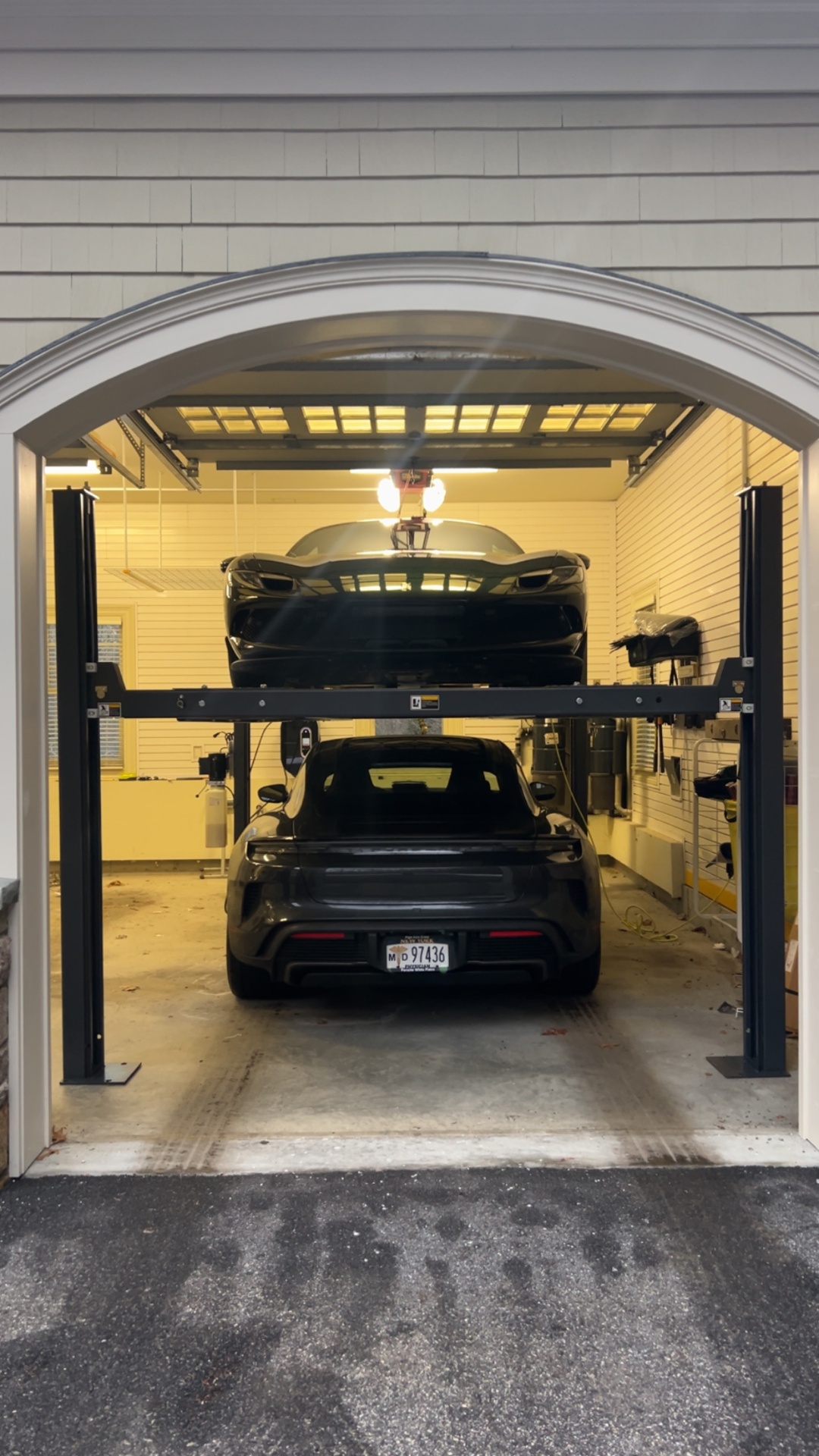 Four-post storage lift with two cars stacked in a residential garage